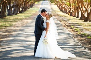 bride and groom kissing driveway trees